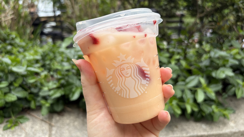 A hand holding a Starbucks Mango Dream Energy Drink