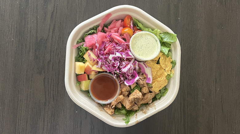 Sweetgreen BBQ chicken salad in to-go container with the sauce inside the bowl