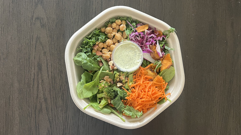 Sweetgreen Super Green Goddess salad in to-go container with the dressing in the center of the bowl