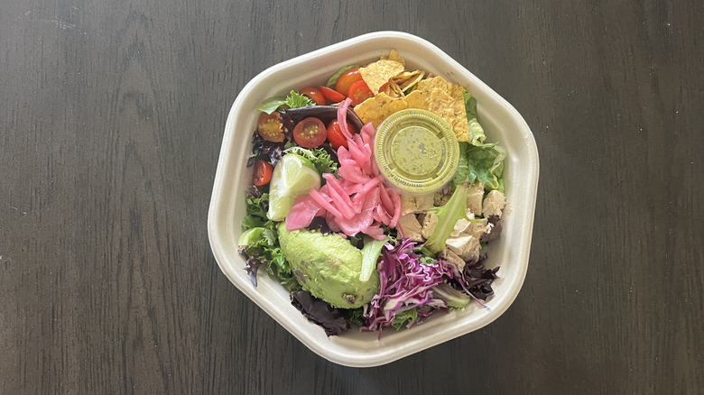 Sweetgreen Guacamole Greens salad in to-go container with various toppings and a dressing inside a plastic cup