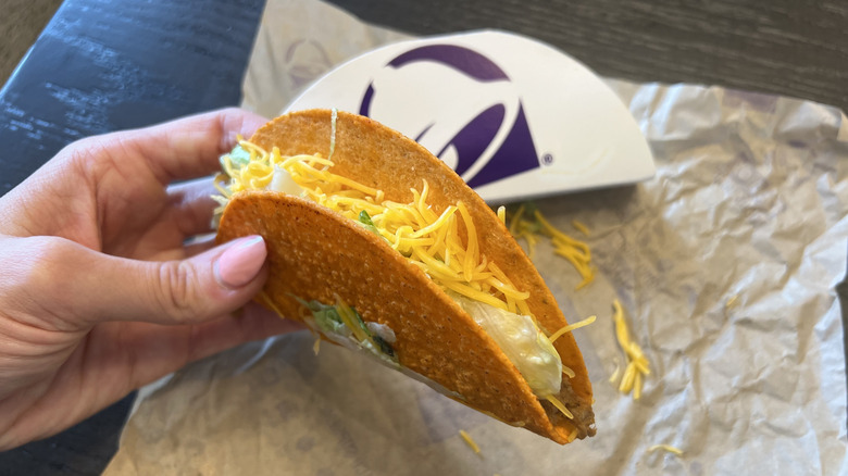 Hand holding Taco Bell Nacho Cheese Doritos Locos Tacos.