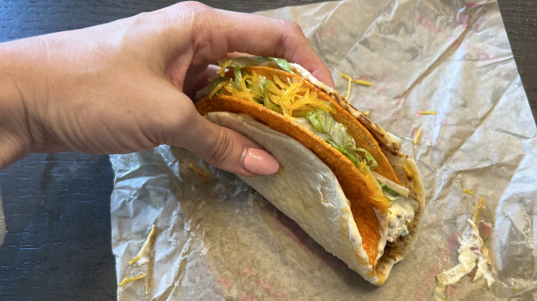 Hand holding Taco Bell Nacho Cheese Doritos Cheesy Gordita Crunch.