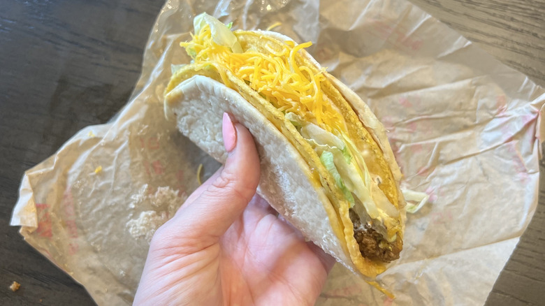 Hand holding Taco Bell Cheesy Gordita Crunch taco.