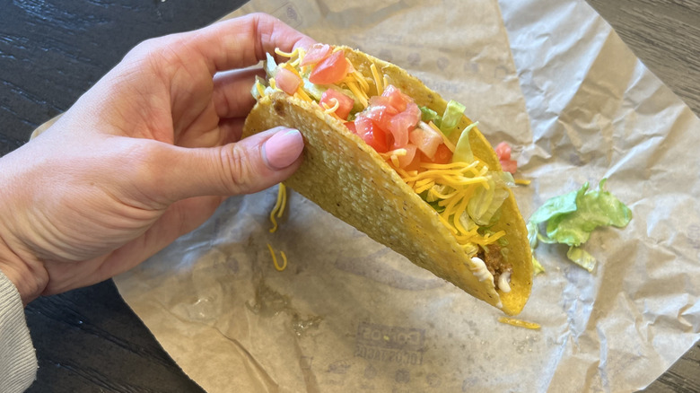 Hand holding Taco Bell crunchy taco supreme.
