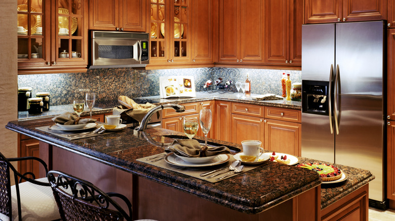 A kitchen has dark granite countertops and warm wood cabinets.