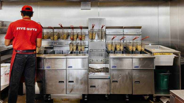 employee at Five Guys frying up baskets of fries