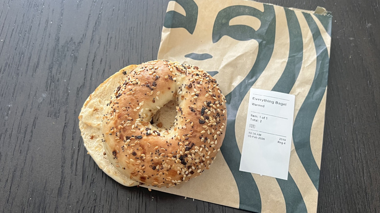 Starbucks everything bagel on take out bag with a receipt on a dark wooden table