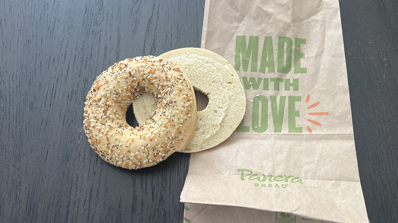 Sliced Panera Bread everything bagel on a take-out bag placed on a dark table