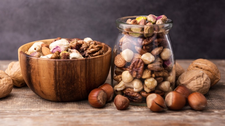A wooden bowl and jar of mixed nuts