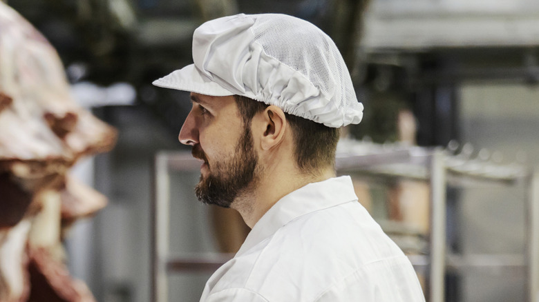 Man inspecting sides of beef