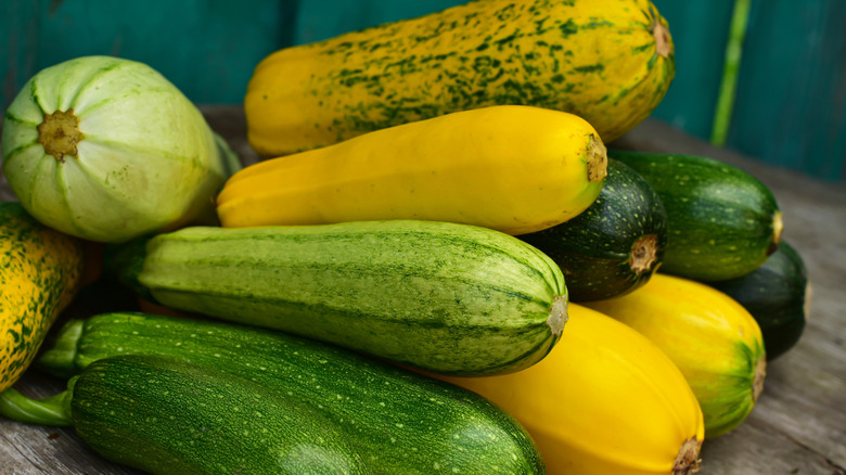 A wide variety of squash stacked up together after being harvested