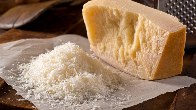 Freshly grated parmesan cheese next to a block of parmesan