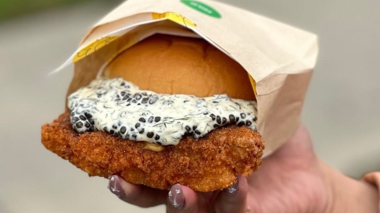 A fried fish sandwich being held in someone's hand