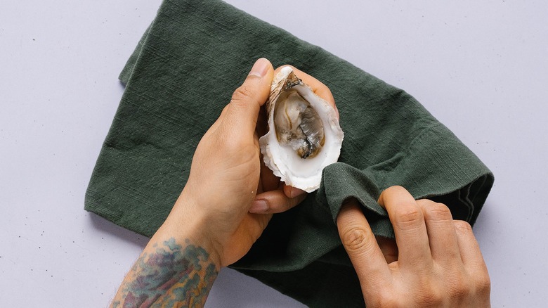 Top-down shot of hand using napkin to clean oyster shell interior