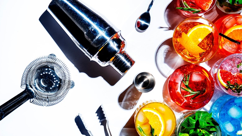 Cocktail shaker on white background with assortment of cocktails