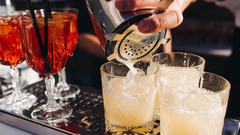Two groups of two different cocktails one being poured