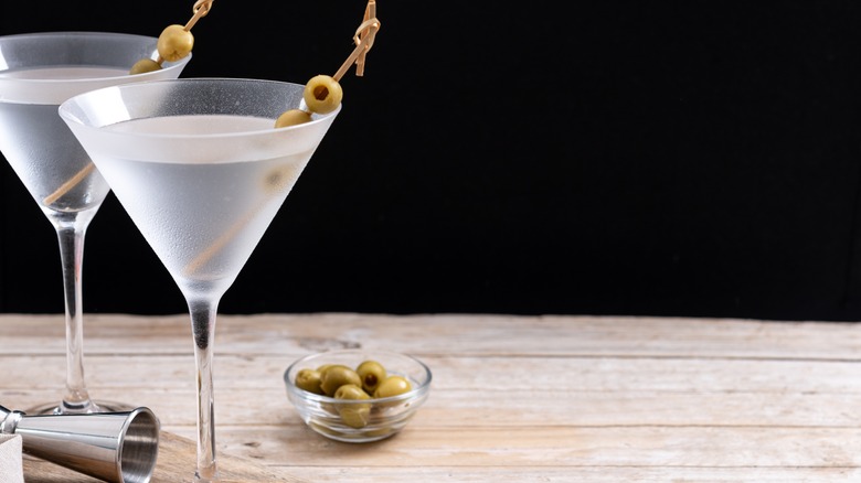 Two vodka martinis with olives on wood surface