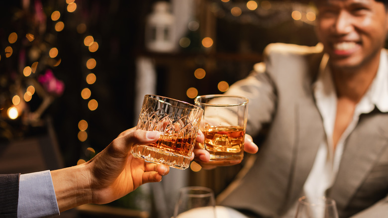 Two people (blurred and unidentified) clinking glasses