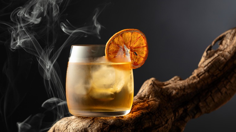 Old fashioned cocktail with dried fruit garnish on wood