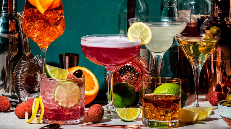 Assortment of cocktails with fruit garnishes and shakers