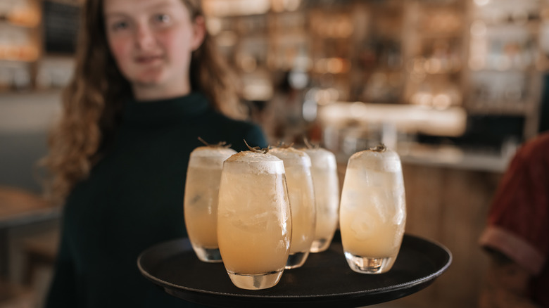 Blurred person carrying five cocktails on a tray