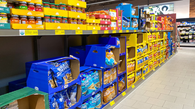 Sauces and chips in coloful shipping boxes on Aldi shelves