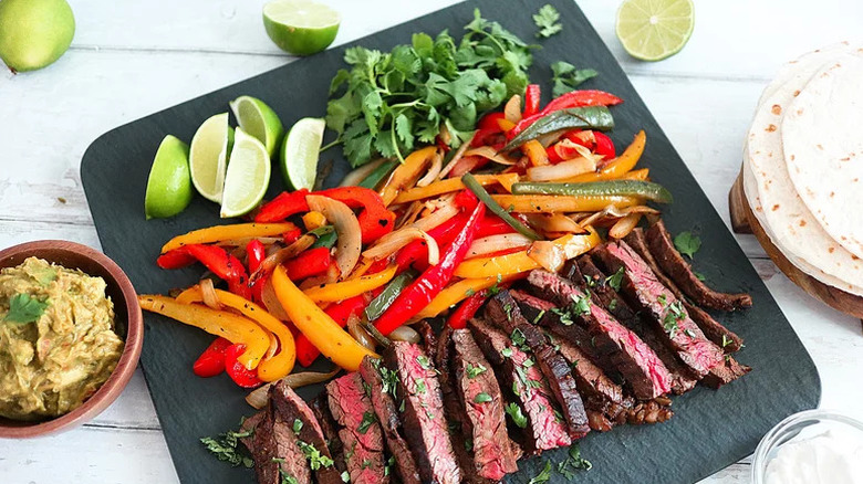 Grilled Steak Fajitas on black board with toppings