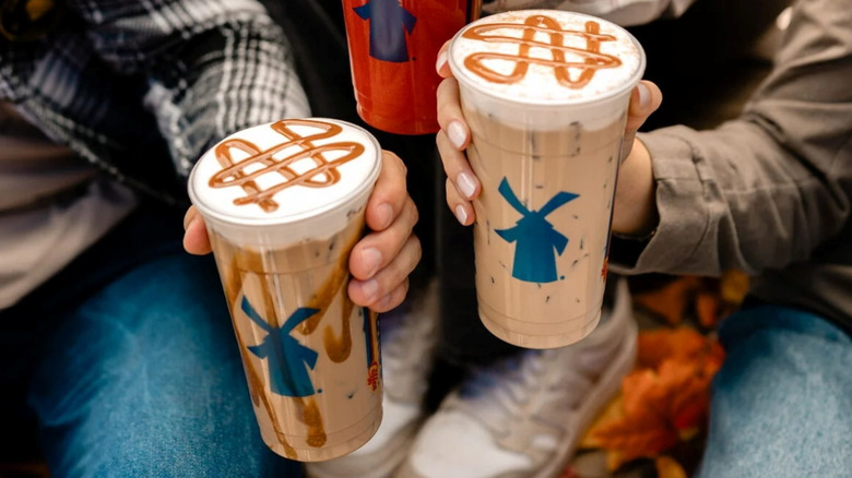 hands holding Dutch Bros Caramel Pumpkin Brûlée and Cookie Butter drinks