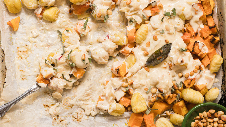 A close up of a spoon in a sheet pan with gnocchi and butternut squash bake