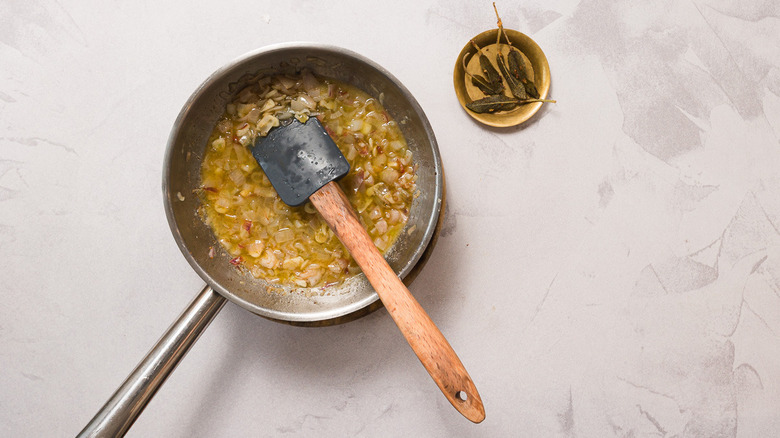 Cooked onions in pan beside fried sage