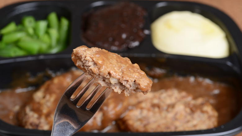 Piece of Salisbury steak on a fork from a TV dinner