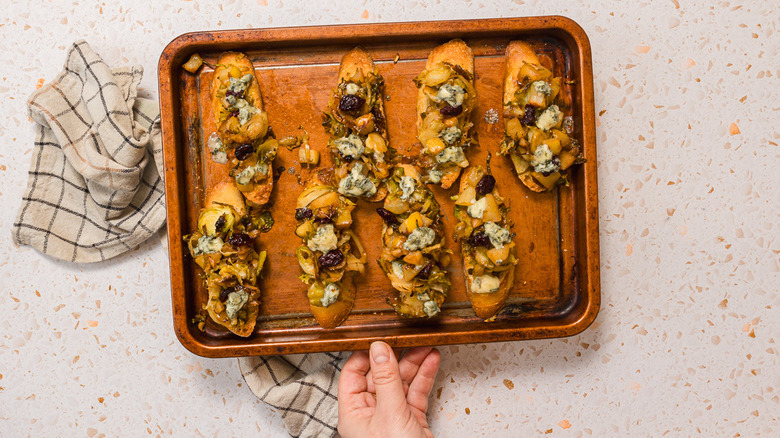 A baking sheet with slices of bruschetta with Brussels sprouts and pears
