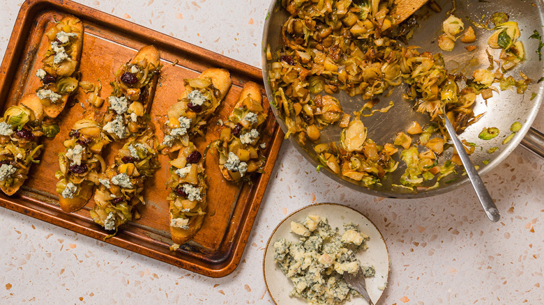 A baking sheet with slices of bruschetta with Brussels sprouts, pears and gorgonzola cheese