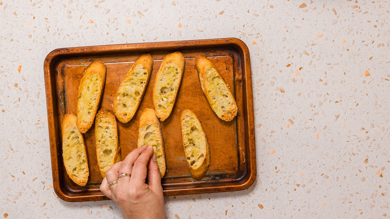 Rubbing toasted baguette slices with garlic