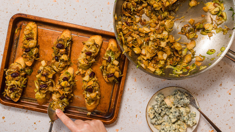 A baking sheet with slices of bruschetta with Brussels sprouts and pears