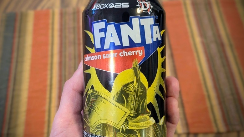 A close-up of a hand holding a can of Fanta Crimson Sour Cherry