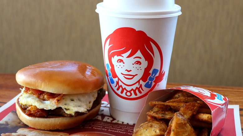 Breakfast sandwich, paper coffee cup, and fried potatoes from Wendy's