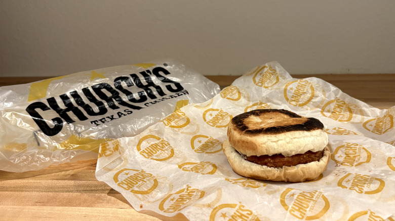 An unwrapped Church's Texas Chicken sandwich with the bag in the background