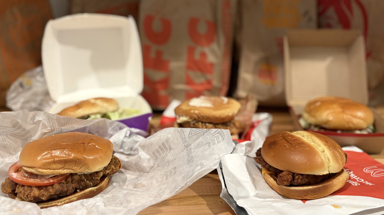 Five unwrapped fast food chicken sandwiches with the bags in the background