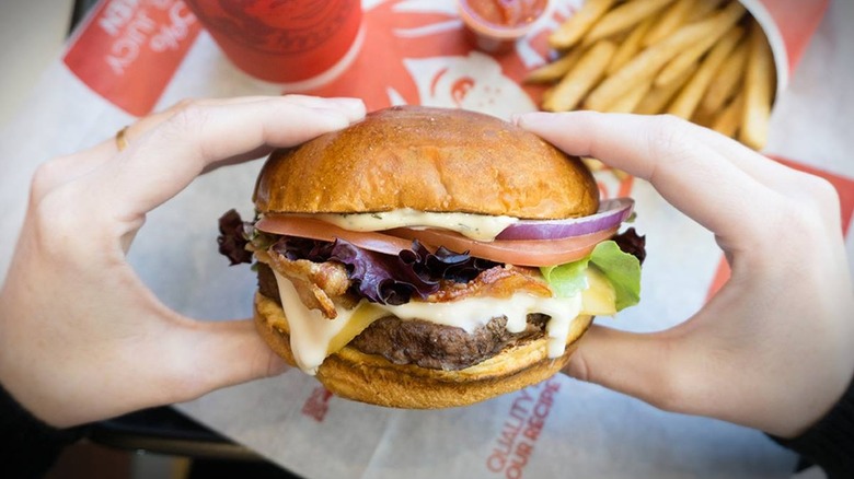 Hands holding Wendy's Gouda Bacon Cheeseburger