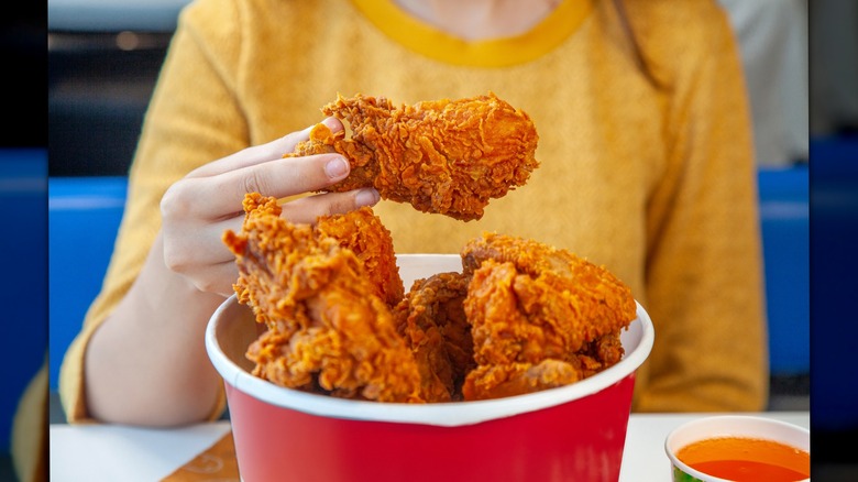 Woman eating a bucket of fried chicken
