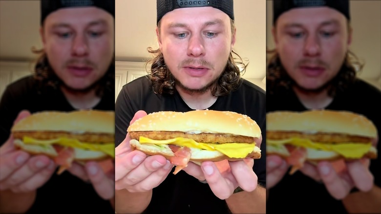 Person holding a Burger King chicken sandwich with bacon and cheese