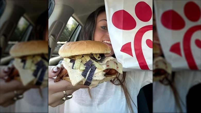 Person holding a Chick-fil-A chicken burger with tortilla strips and a creamy sauce