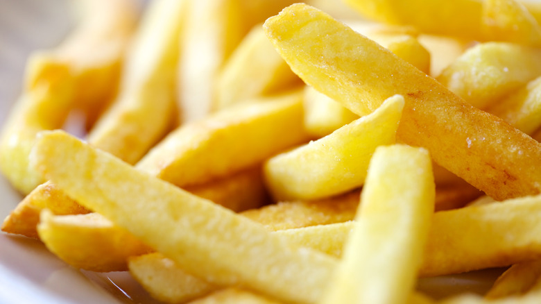 Close-up of fast food French fries in a white paper wrapper