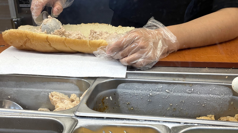 Close up of a worker at Subway making a tuna sandwich