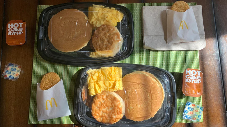Two McDonald's Big Breakfast with Hotcakes containers laid out nicely on table on a green placemat