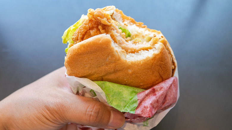 Hand holding chicken sandwich in wrapper