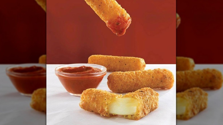 Arby's mozzarella sticks served with a small container of marinara sauce