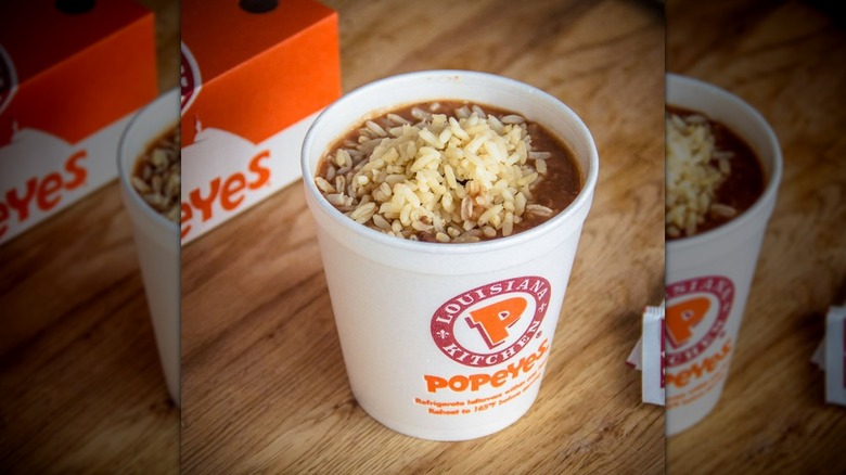 Tub of Popeyes red beans and rice on a wooden tabletop