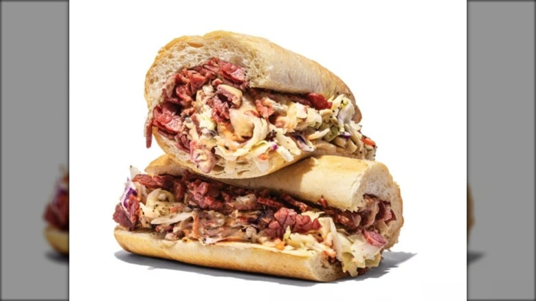 Stacked sub sandwich with pastrami, coleslaw, and Swiss cheese